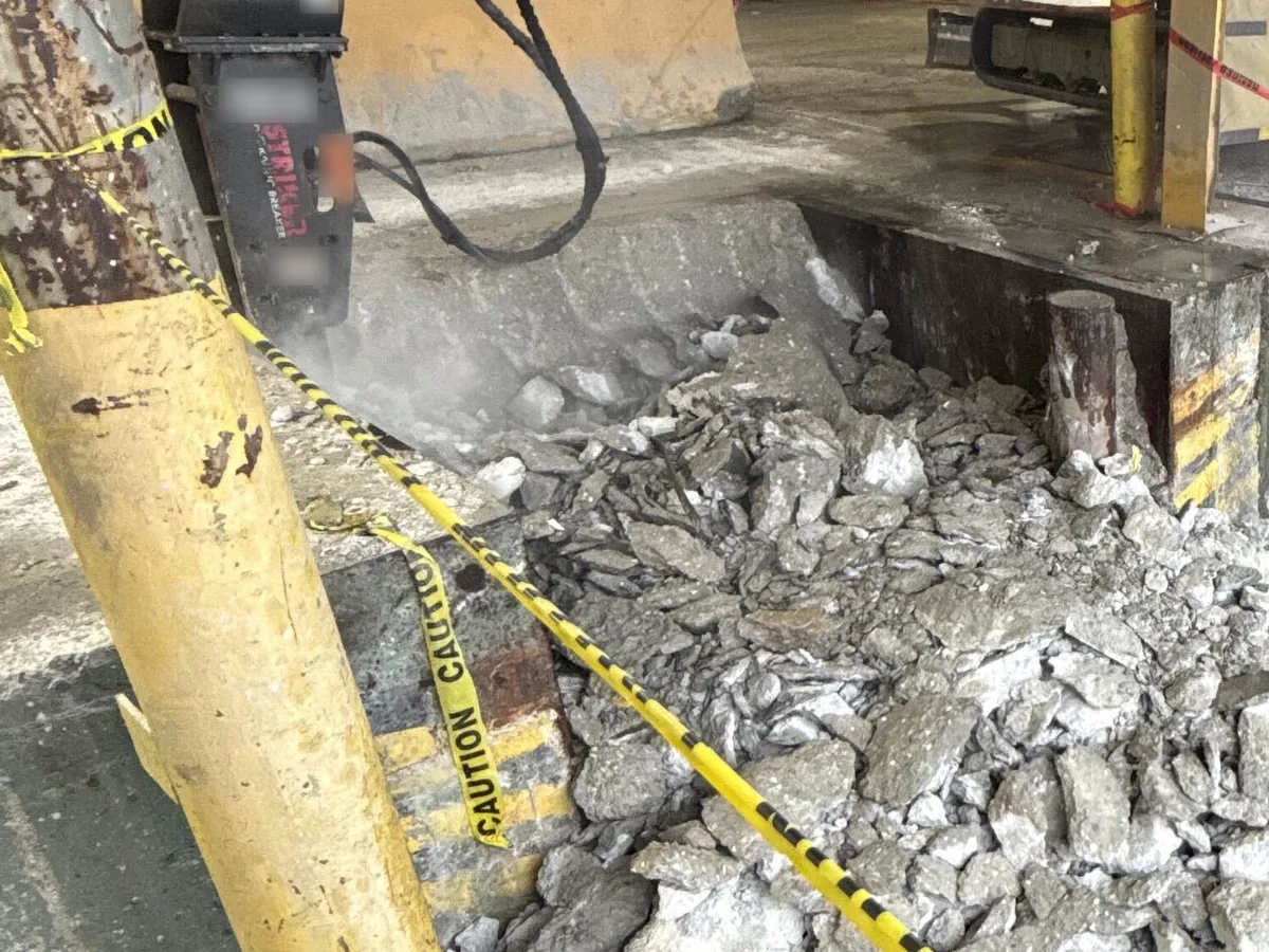 Hydraulic breaker on a mini excavator breaking out an old concrete slab into rubble, concrete removal and replacement