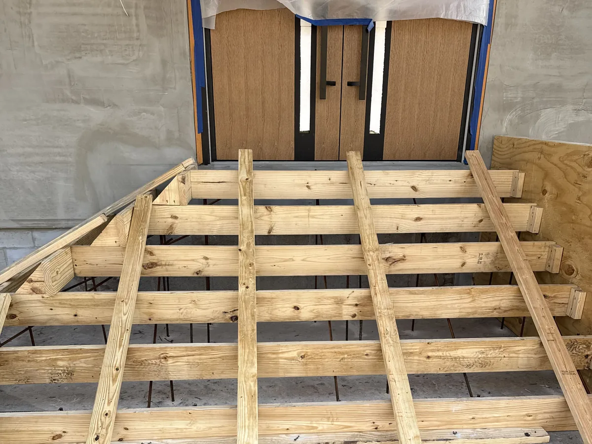 Stepped wood forms braced at a doorway with rebar set inside before the concrete pour, concrete foundations and footings