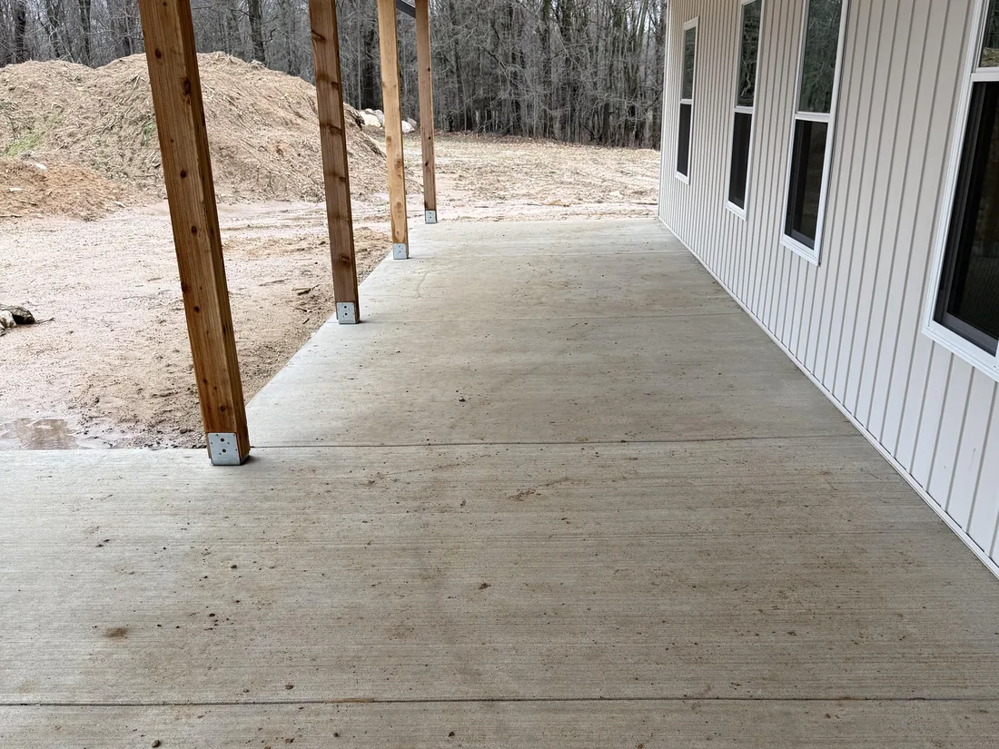 New concrete slab under a long covered back porch with wood posts, concrete patios and walkways