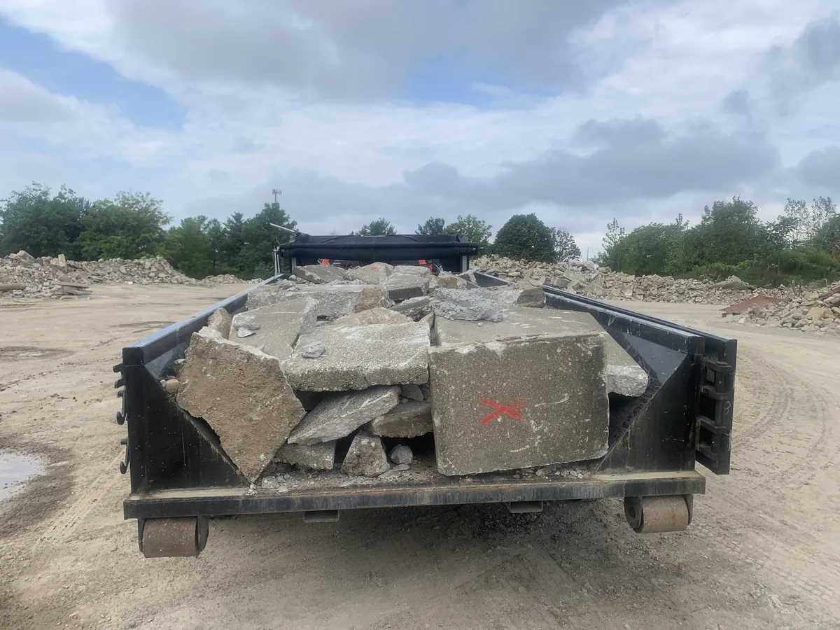 Broken concrete slab pieces loaded in a container for haul-off at a concrete recycling yard, concrete removal and replacement